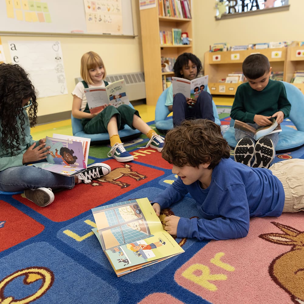 Children sitting on floor reading Fundations readers