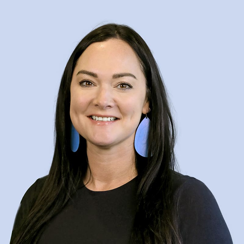Makenzie Buhman smiling at camera and wearing blue earings and a black top