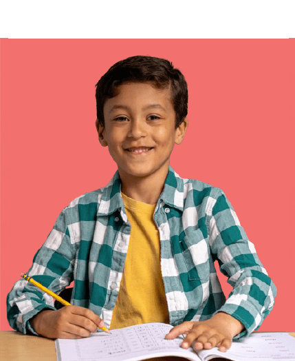 Young boy in a green plaid shirt smiles at the camera while holding a pencil and working in a workbook.
