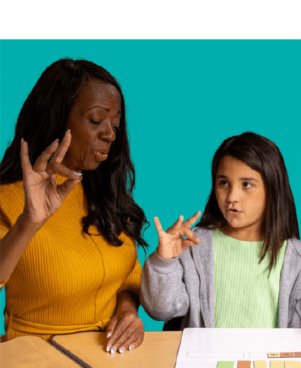 Adult woman and young girl seated at a desk, both using hand gestures to communicate, with a teal background.